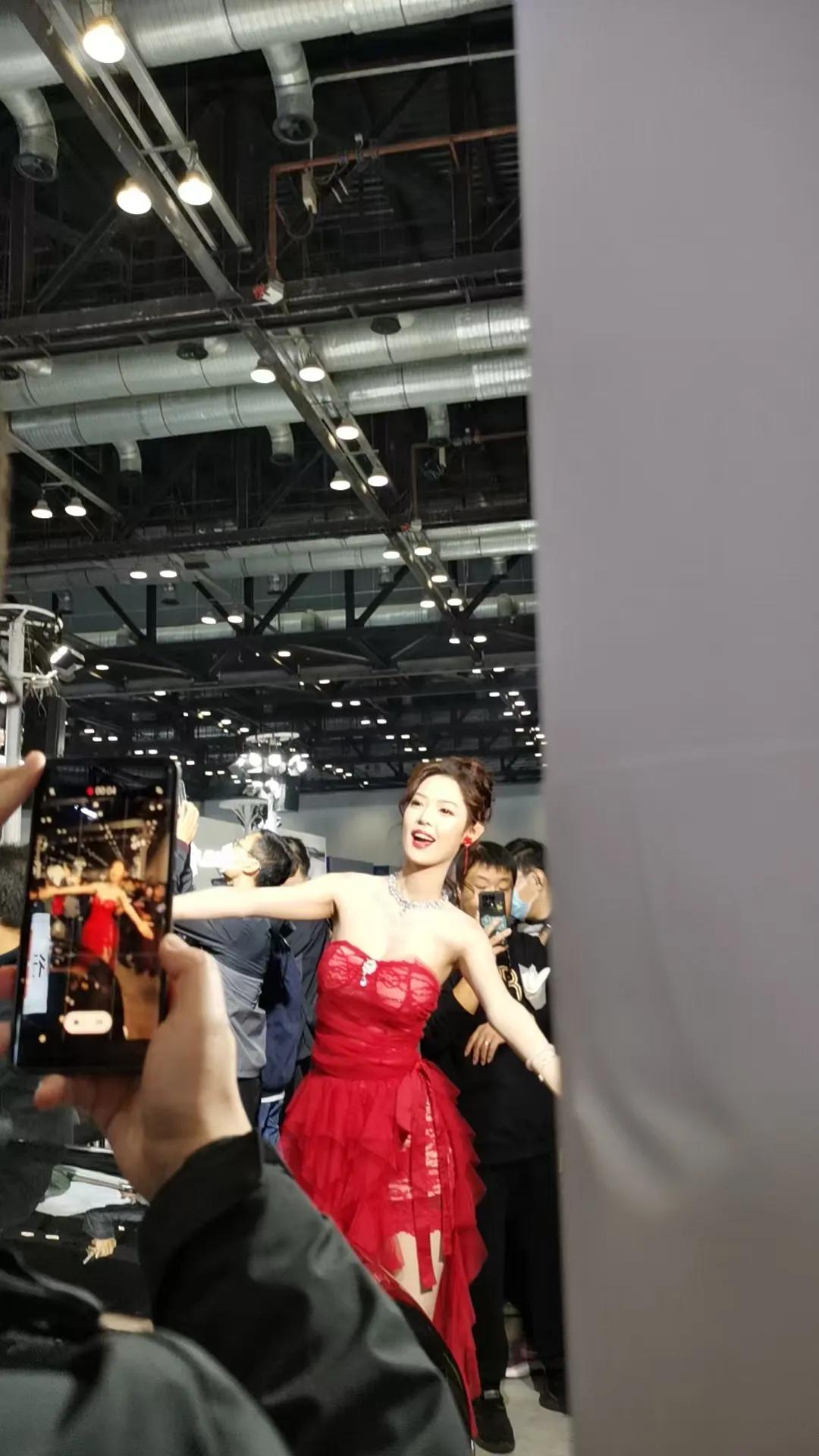 车展现场人潮涌动，镜头里这一身红色抹胸纱裙格外亮眼。
红裙衬得气质明艳大方，站在