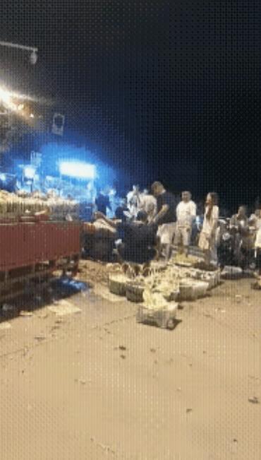 男子把西瓜高高举起，重重地摔在摊主的头上，一连摔了多个西瓜，摊主始终坐在那里，任