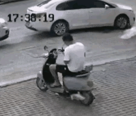 风中的塑料布纠缠上了骑电动车的男子。这场景，透着一股诡异气氛。