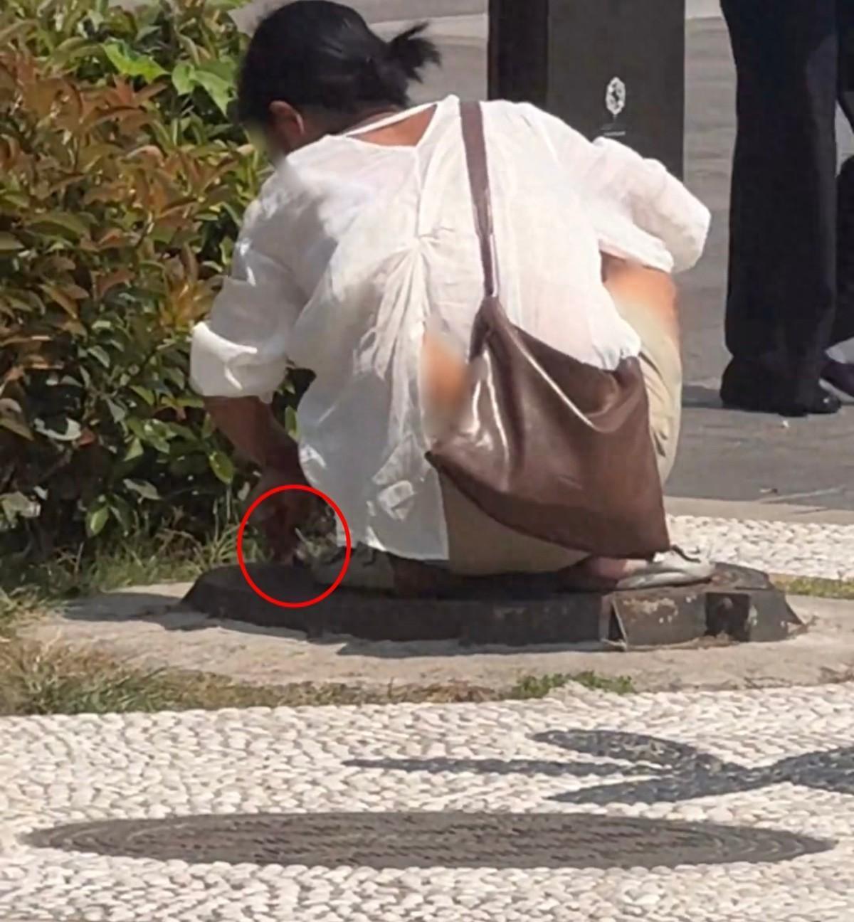 陕西西安，有人在大雁塔景区拍到，一名女子在步行街，偷偷向街边雨水井小孔塞入很多根