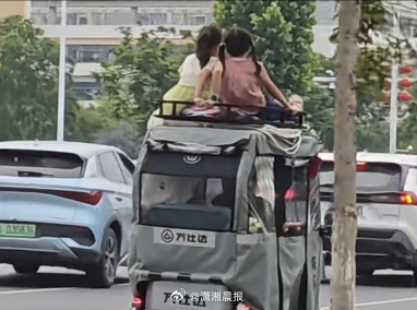 【湖北一#三轮车车顶载两小孩在车流中行驶#，无任何防护，#当地回应车顶载两小孩在