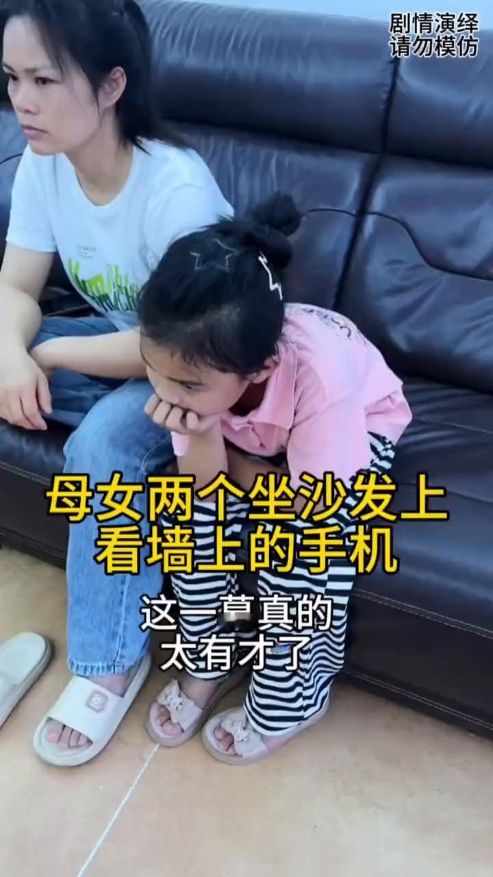 母女两个坐沙发上看墙上的手机，这一幕真的太有才了。
丈夫从母女两个身边走过，这时