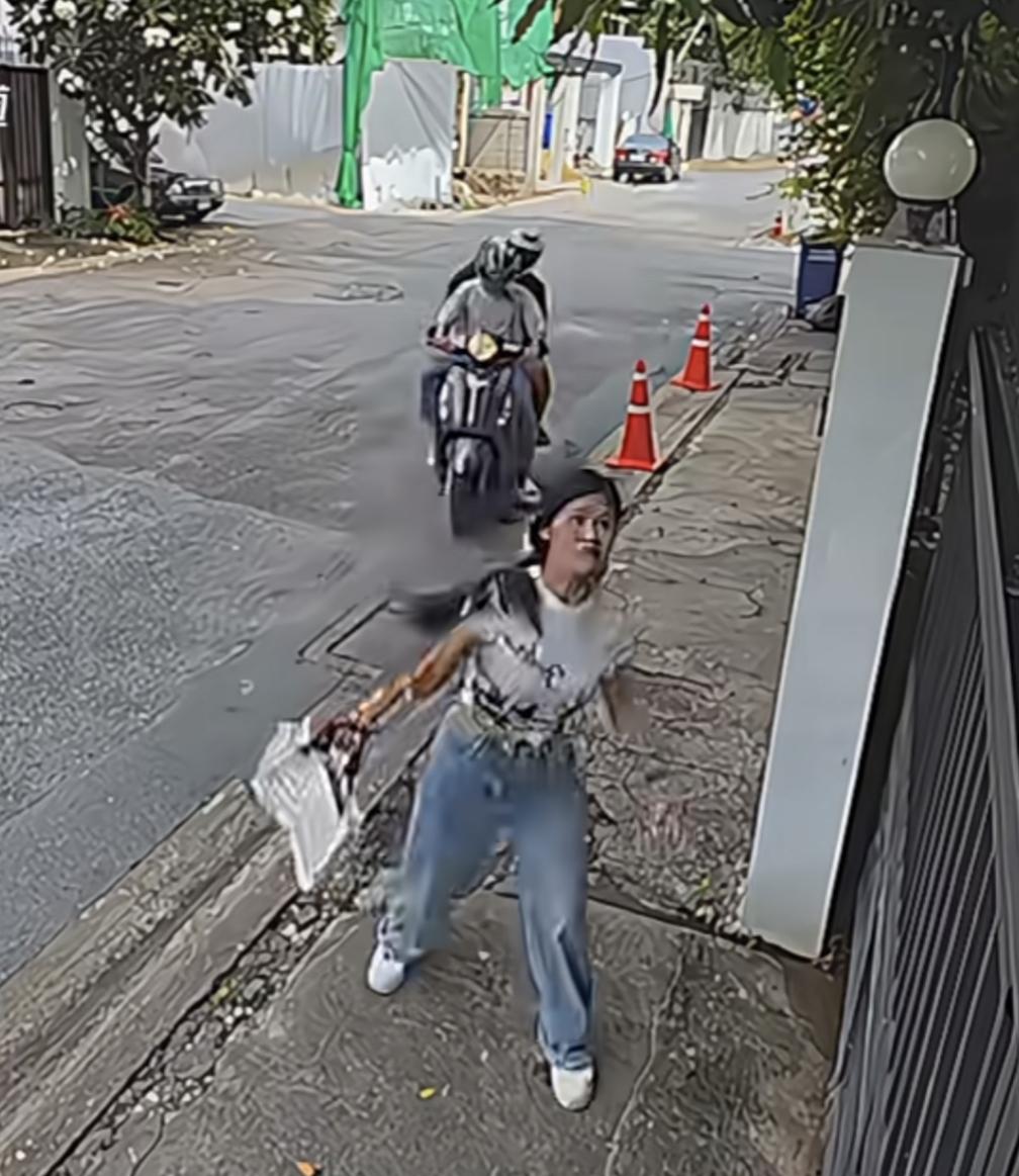 女子看见两个男人骑摩托车过来，
直接把手里的包扔进“劫匪”的家，
两男子一脸懵，