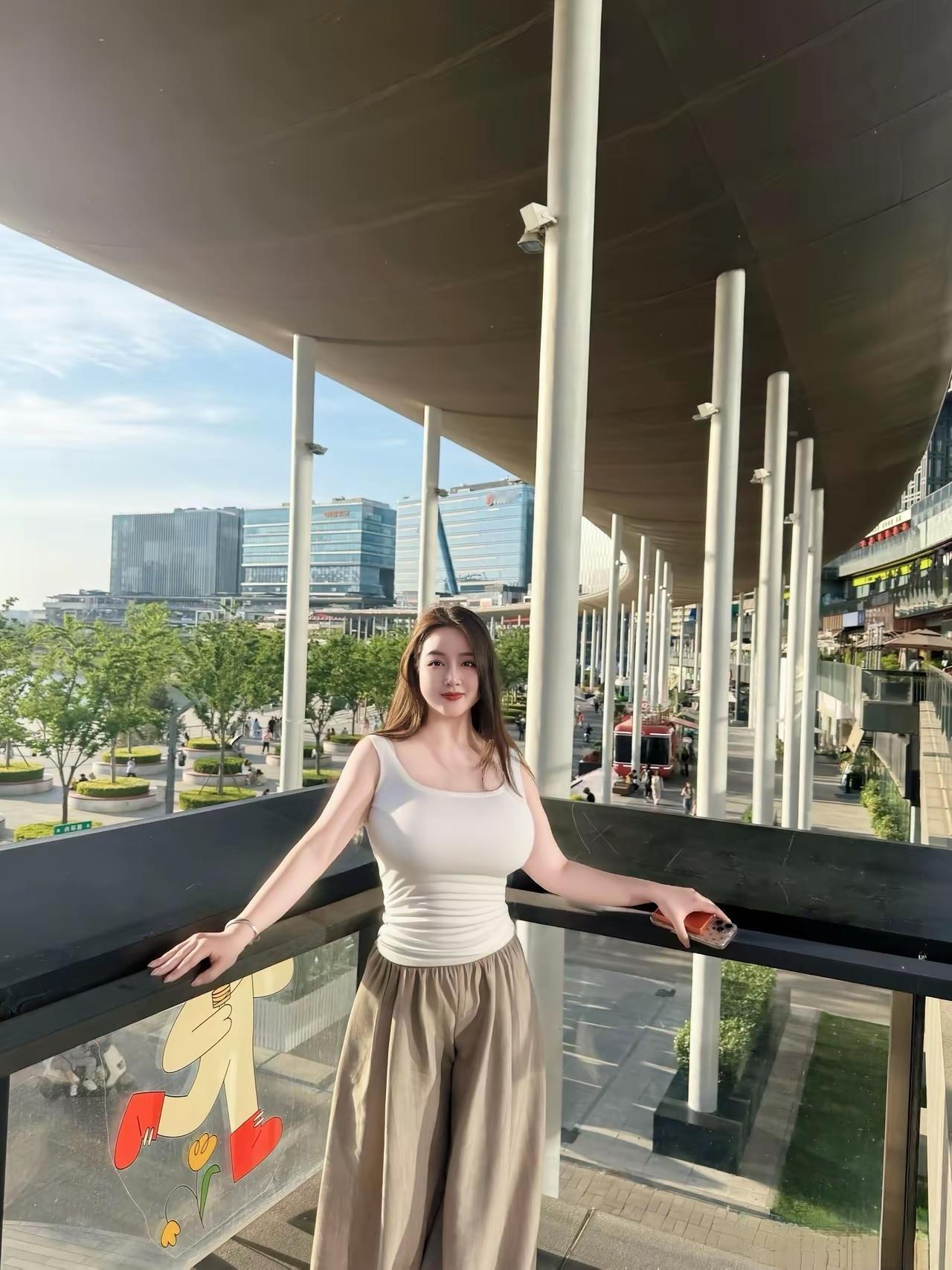 都市少女在现代建筑前，享受阳光与美景