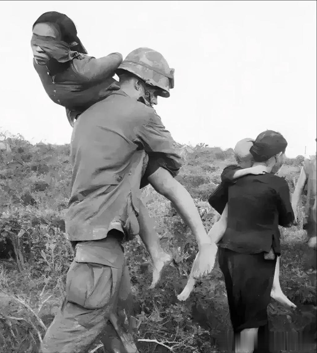 越南战争时期，一名被俘的越南女兵被美军扛回基地，照片中，美军为确保基地位置不被泄