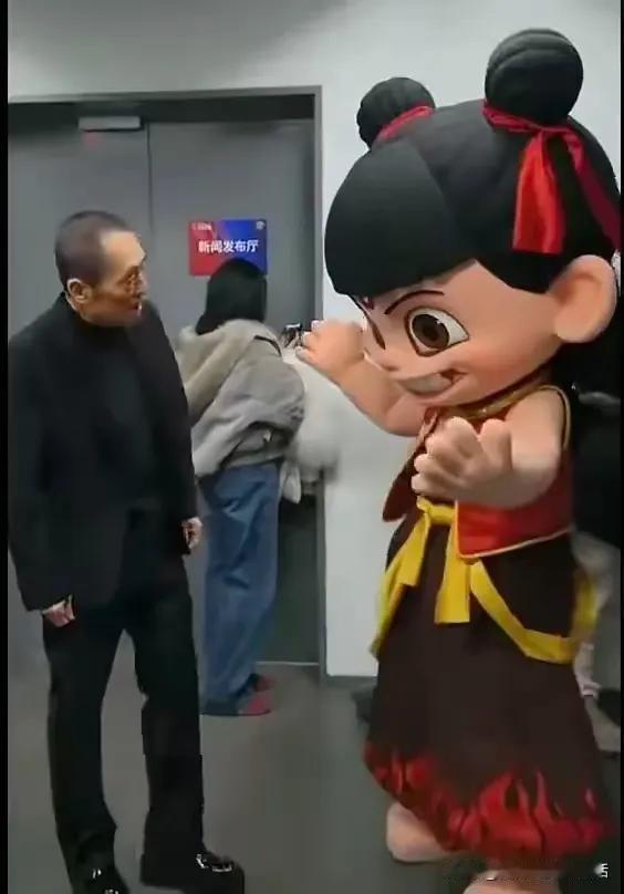 看看这张照片
张艺谋导演此时是什么心情呢？
满脸的疑惑和不解…
就一个动画娃娃，