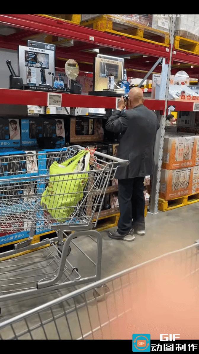 上海，山姆会员商店，一光头老人走到剃须刀展示区，拿起一把电动剃须刀仔细端详。
反