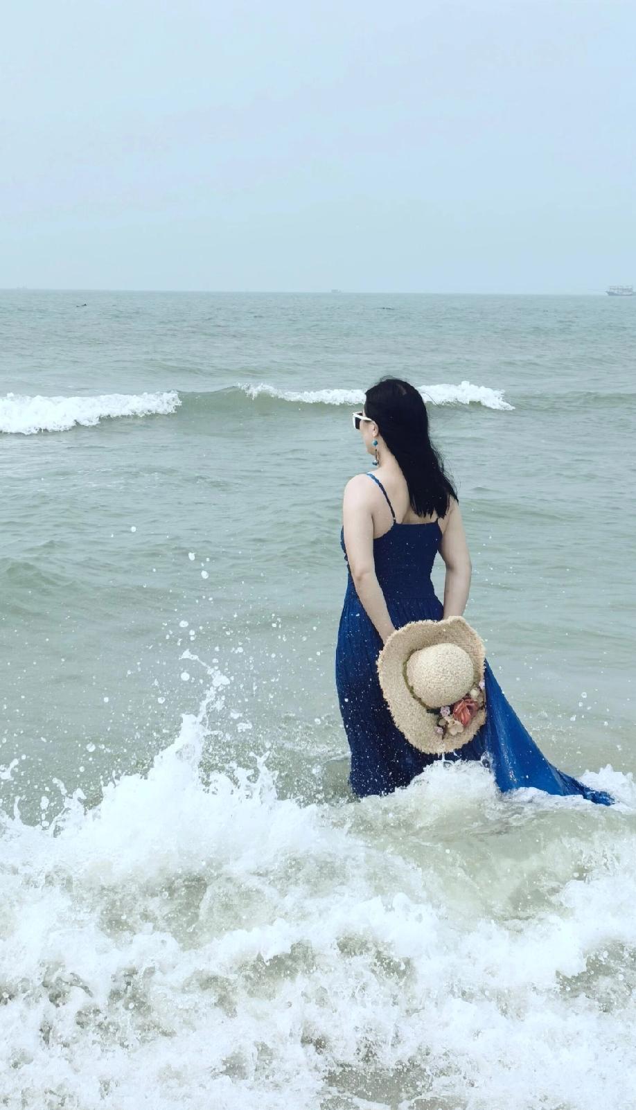 海边漫步，蓝色长裙与海浪相映成趣，享受宁静时光。