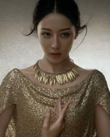 迪丽热巴此次的妆造以金色为主调，展现出高贵典雅的女神气质。
照片中的她，身着金色