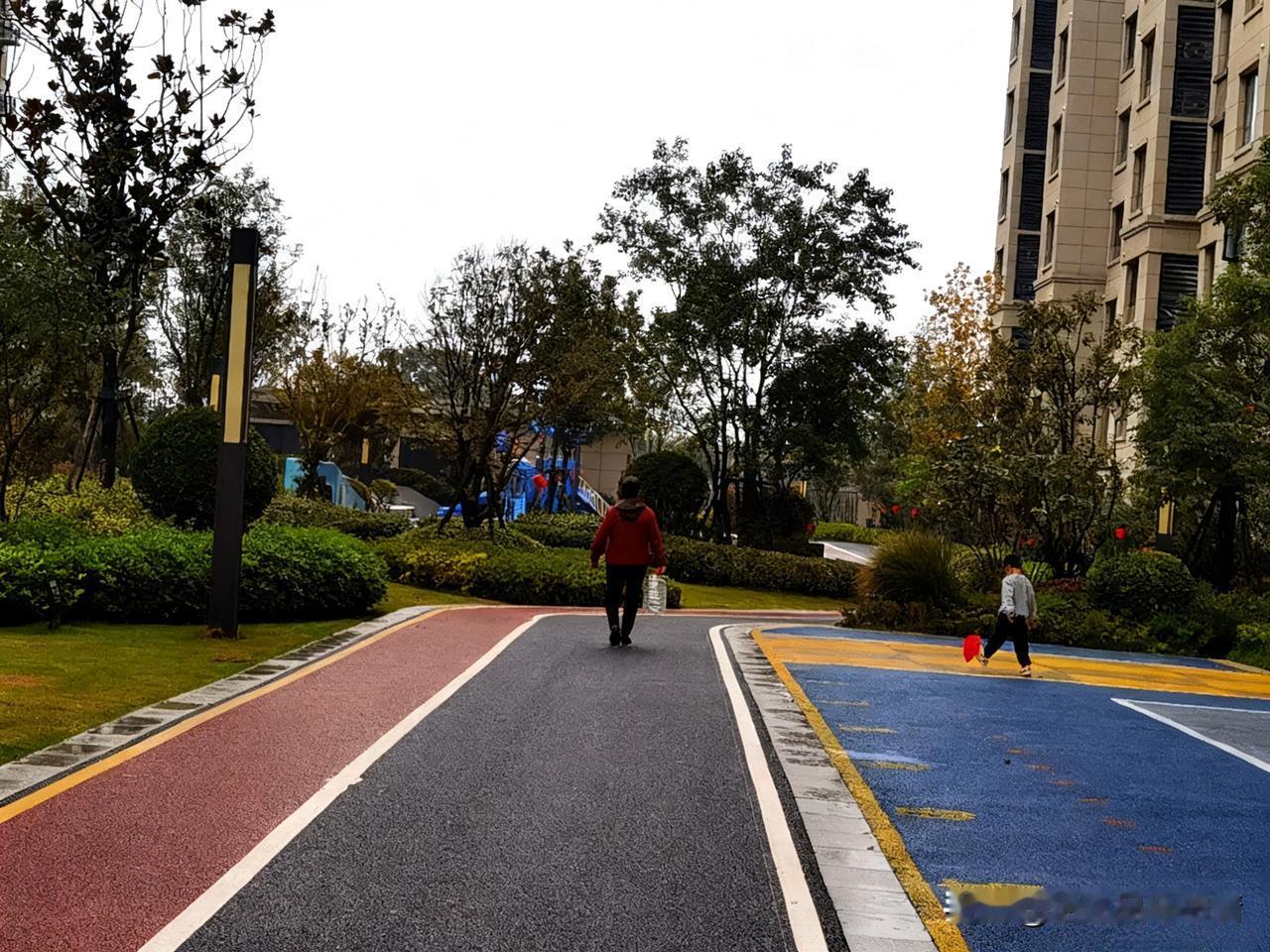 雨后的小区，空气格外清新。彩色的步道被雨水冲刷得干干净净，一位行人慢悠悠地走着。