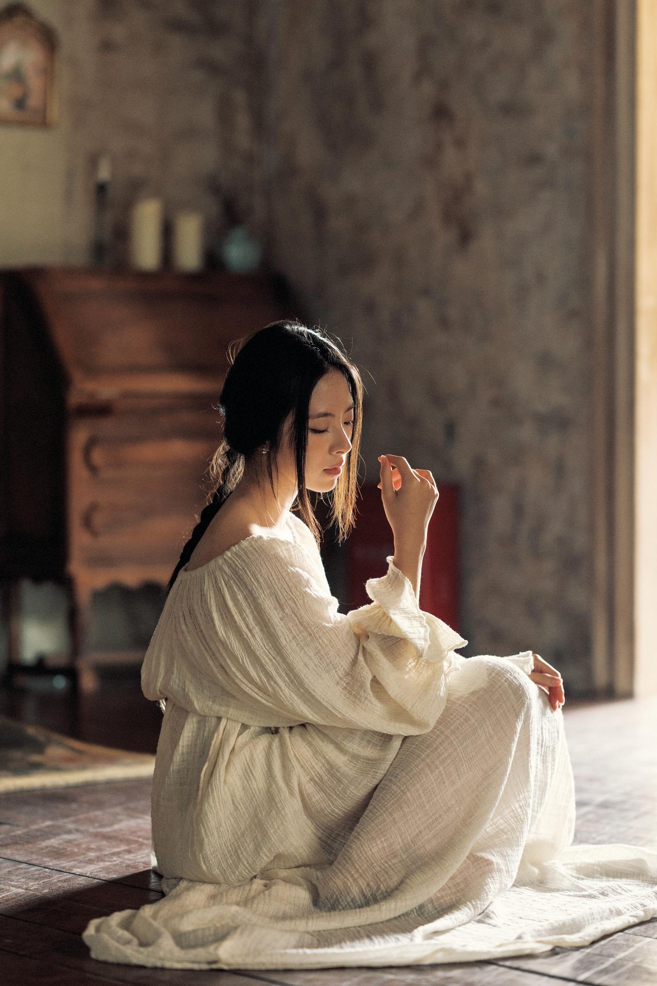 照片以“薄纱裹身”的造型，将逆光的氛围感推向极致。侧逆光穿透层叠的纱料，在人物身