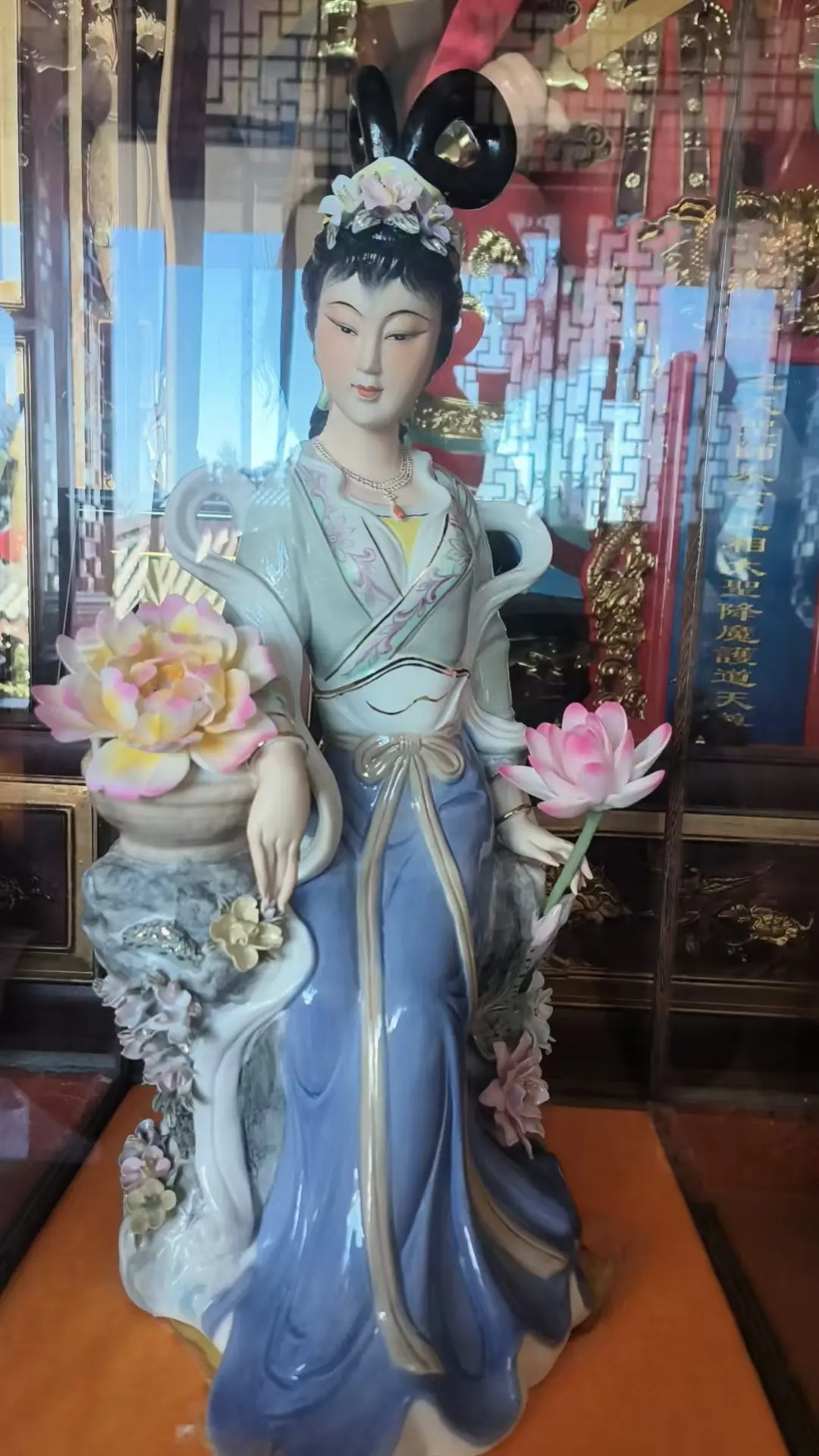 瓷塑仙娥倚石旁， 荷香花影映霓裳。 凝眸浅笑含春韵， 福满人间岁月长。
