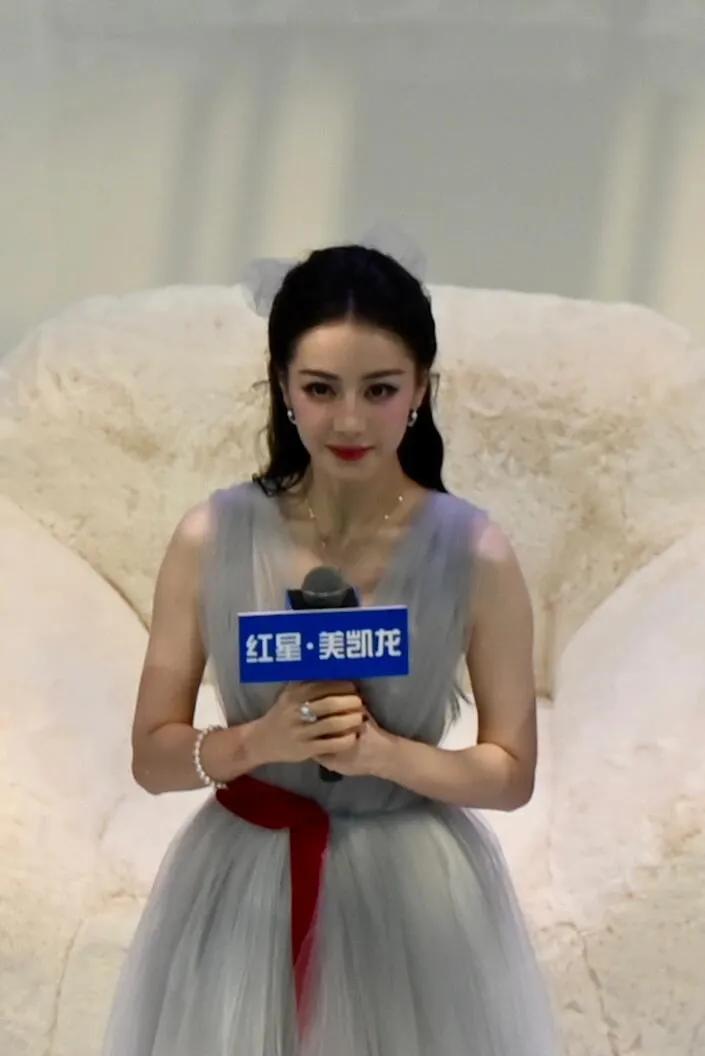 迪丽热巴坐毛绒沙发上，浅灰纱裙轻盈如梦，红丝带点睛，整个人仙到发光✨ 五官精致得
