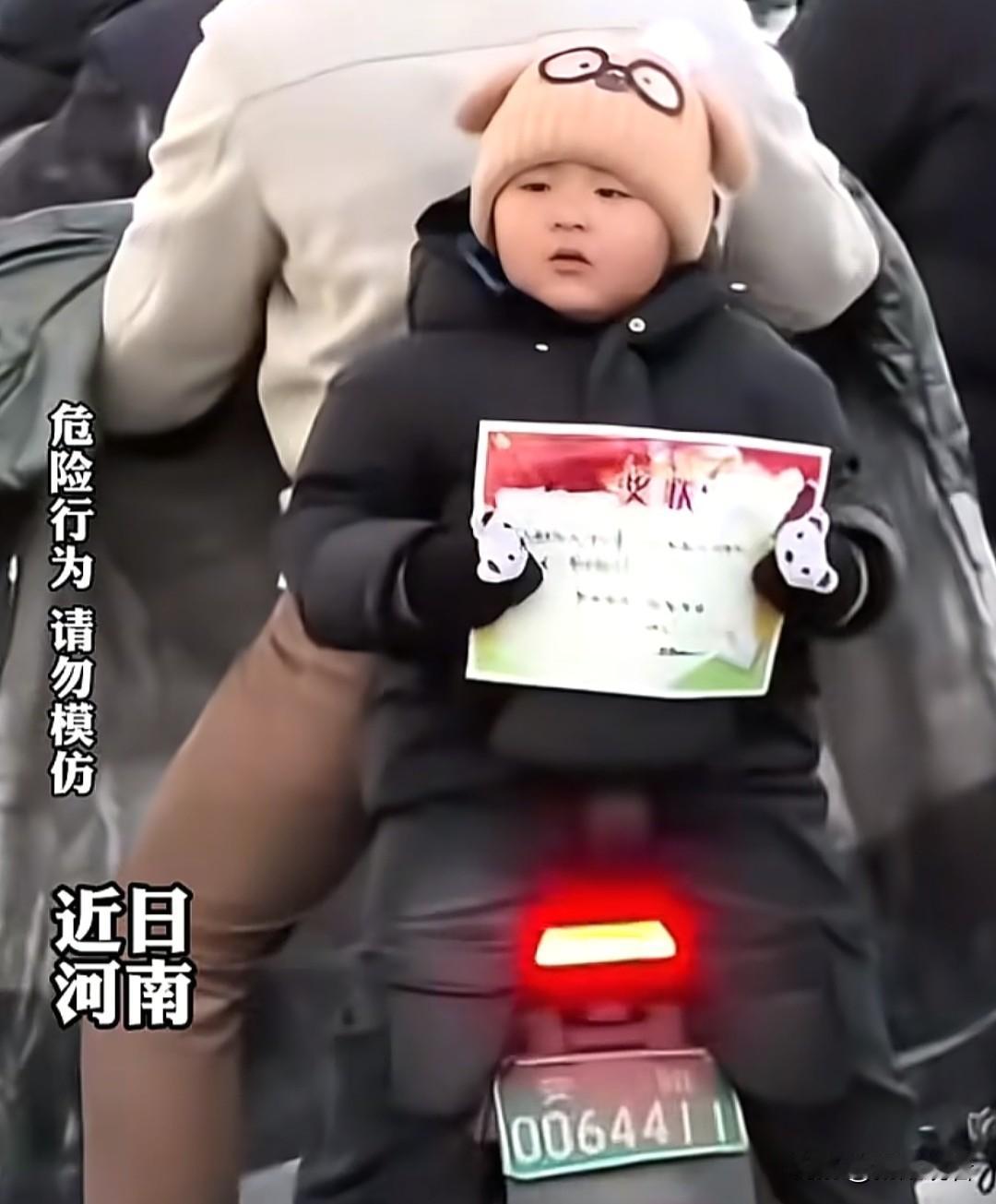 河南娃举着奖状在后座花式炫耀，爸爸让装起来，娃理直气壮回“我已经装起来了”，主打