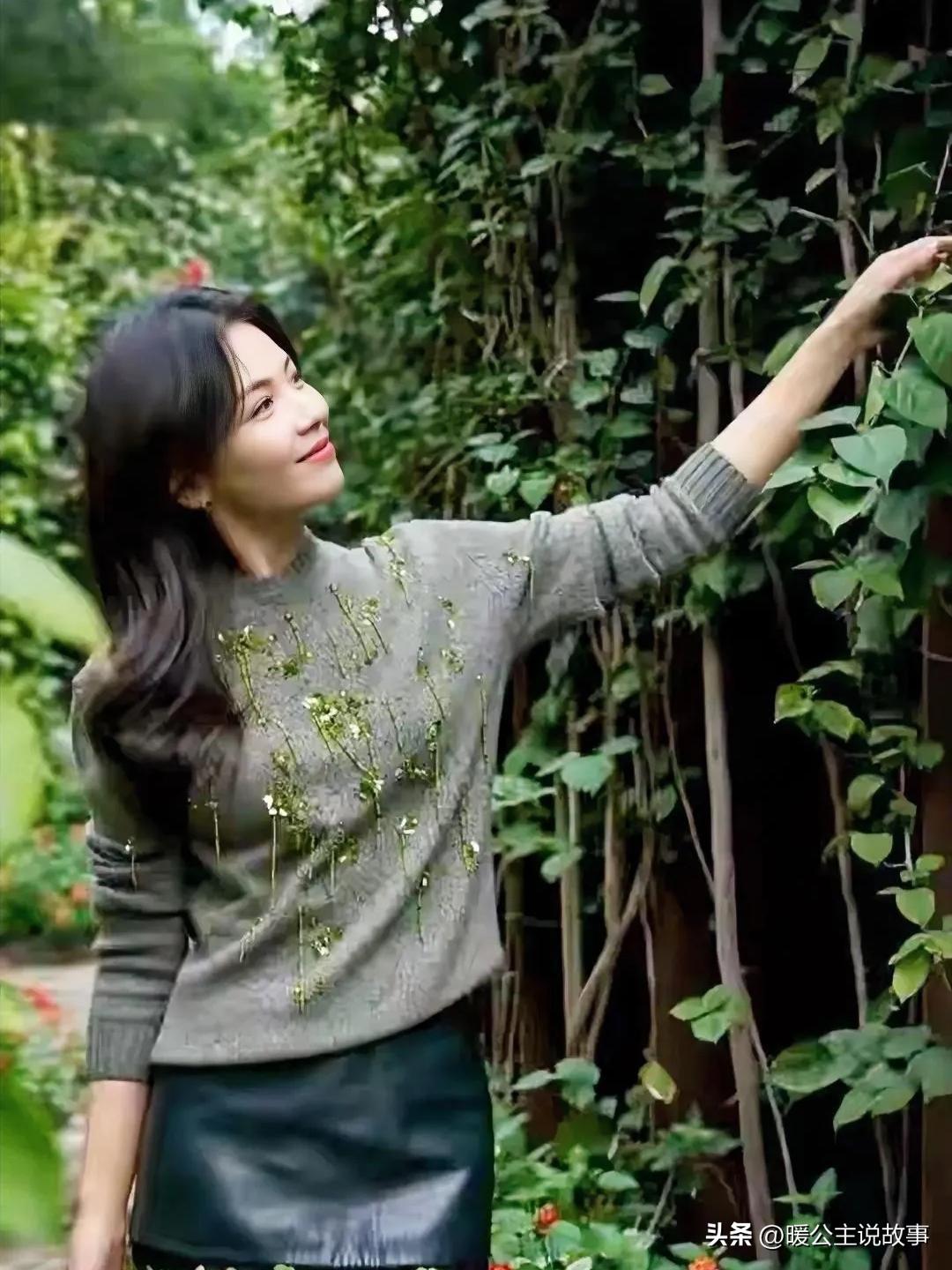 刘涛一身灰色毛衣配黑色皮裙，往绿植堆里一站，休闲范儿直接拉满，看着就特别放松舒服