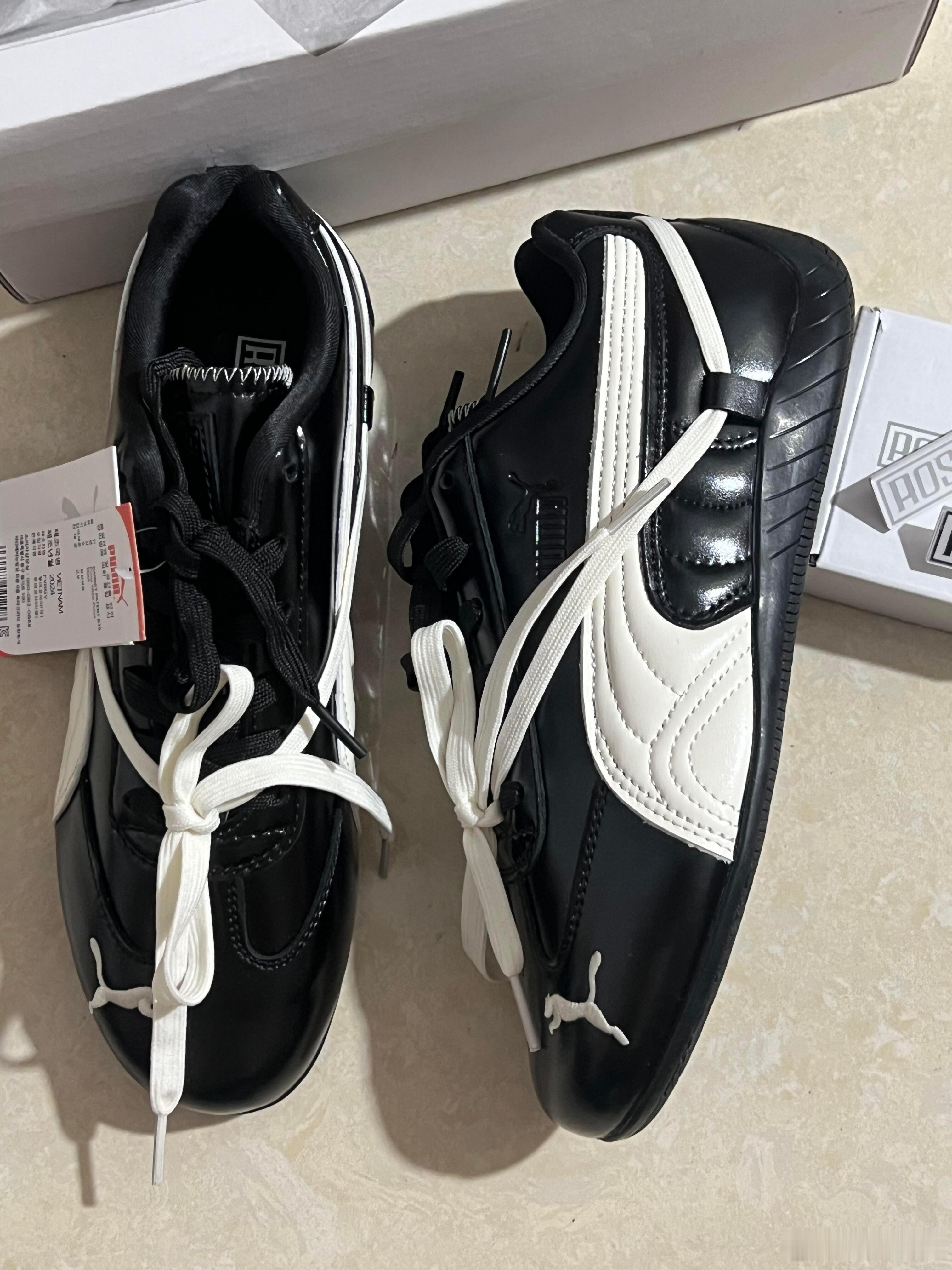 这是一双设计经典的黑白配色PUMA赛车鞋。鞋身采用光泽感十足的黑色皮革制成，侧面