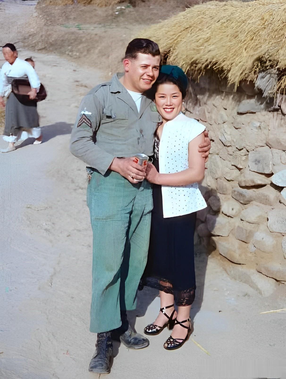 60年代，驻韩美军的军营外，一名美军抱着为其提供特殊服务的韩国女子，他们笑得很开
