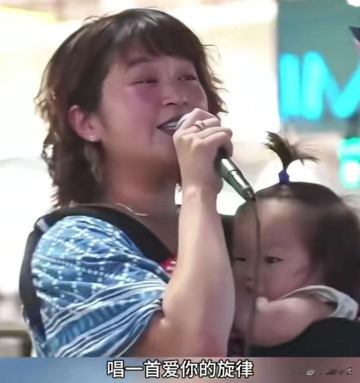 场景着实令人动容！
在广州的大街上，一位母亲怀抱着婴儿，正卖力地唱歌谋生。那饱含