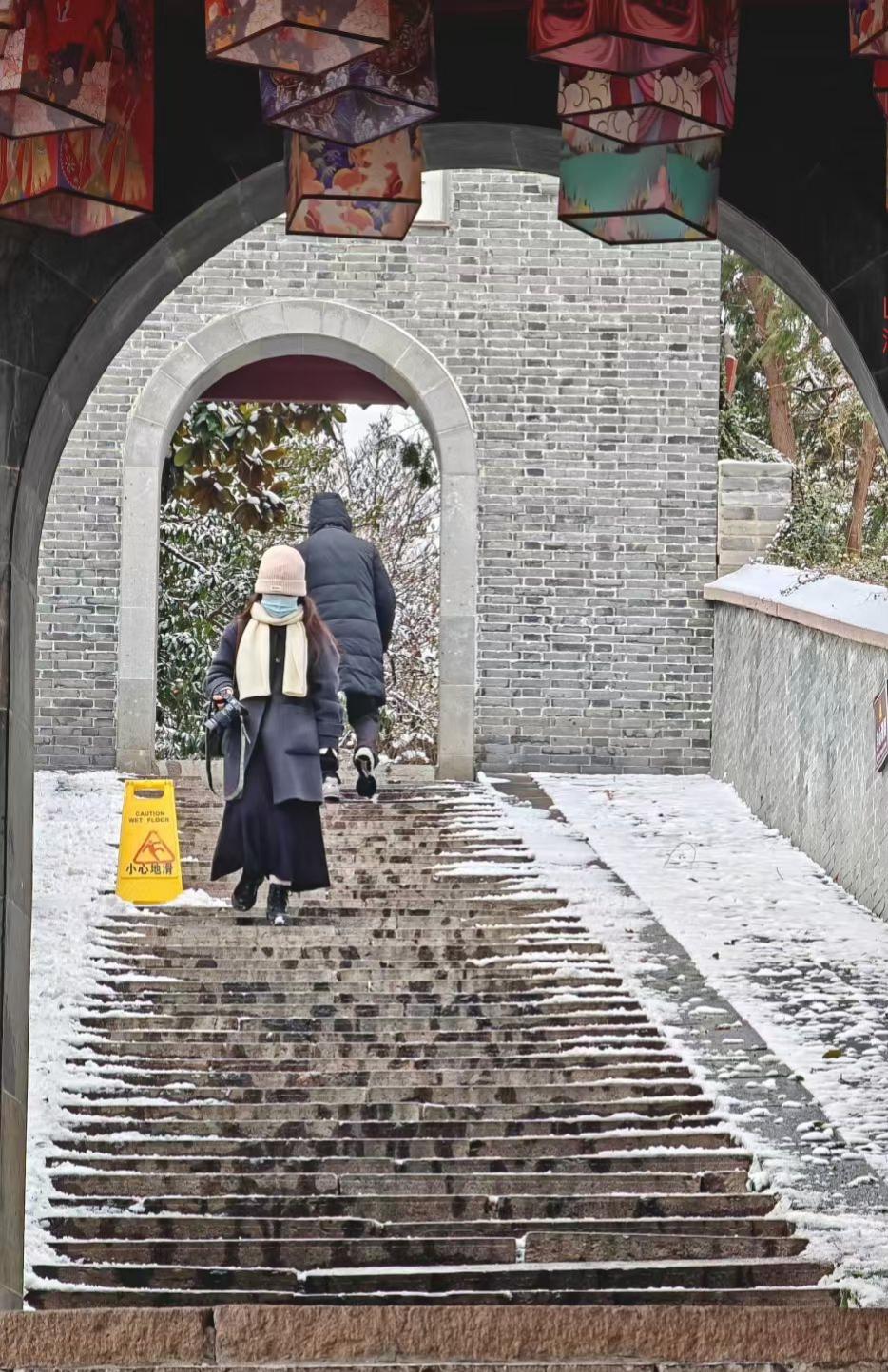 雪在古阶上织了层薄绒，灯笼垂着彩影，行人踏碎的不是冰，是冬日光阴里的静谧絮语。