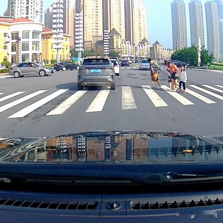 有的车过线不减速，有的车稳稳停住还挥手示意；有的行人大步快走，有的行人在斑马线上