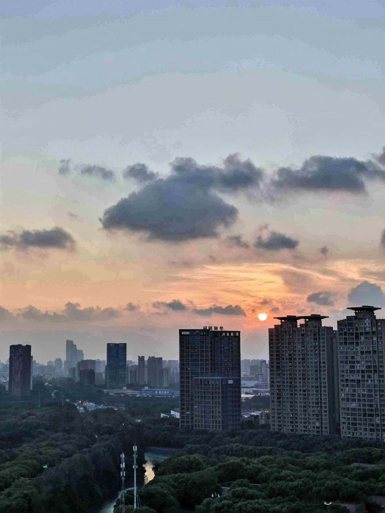拨云见日，久违的夕阳终于现身，落日余晖洒在高楼与绿树间，橘色晚霞铺满天空。

雨