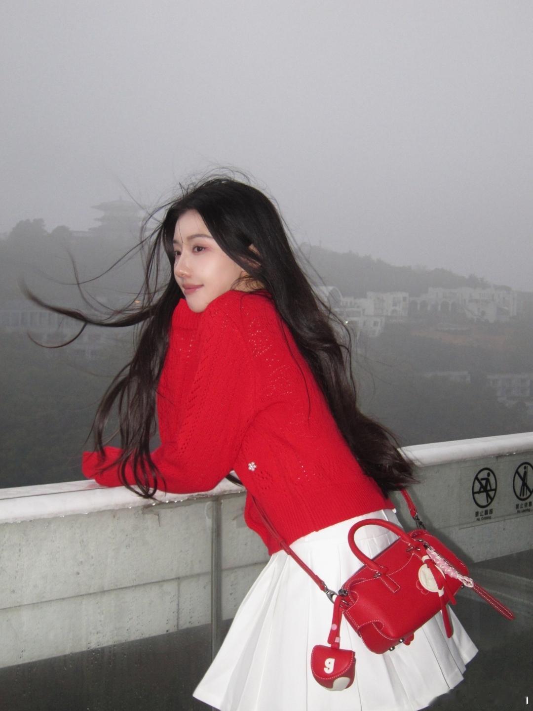 薄雾漫山，风拂发梢，王鹤润一身红白撞色穿搭立于山间观景台，在朦胧烟岚里，撞出了最