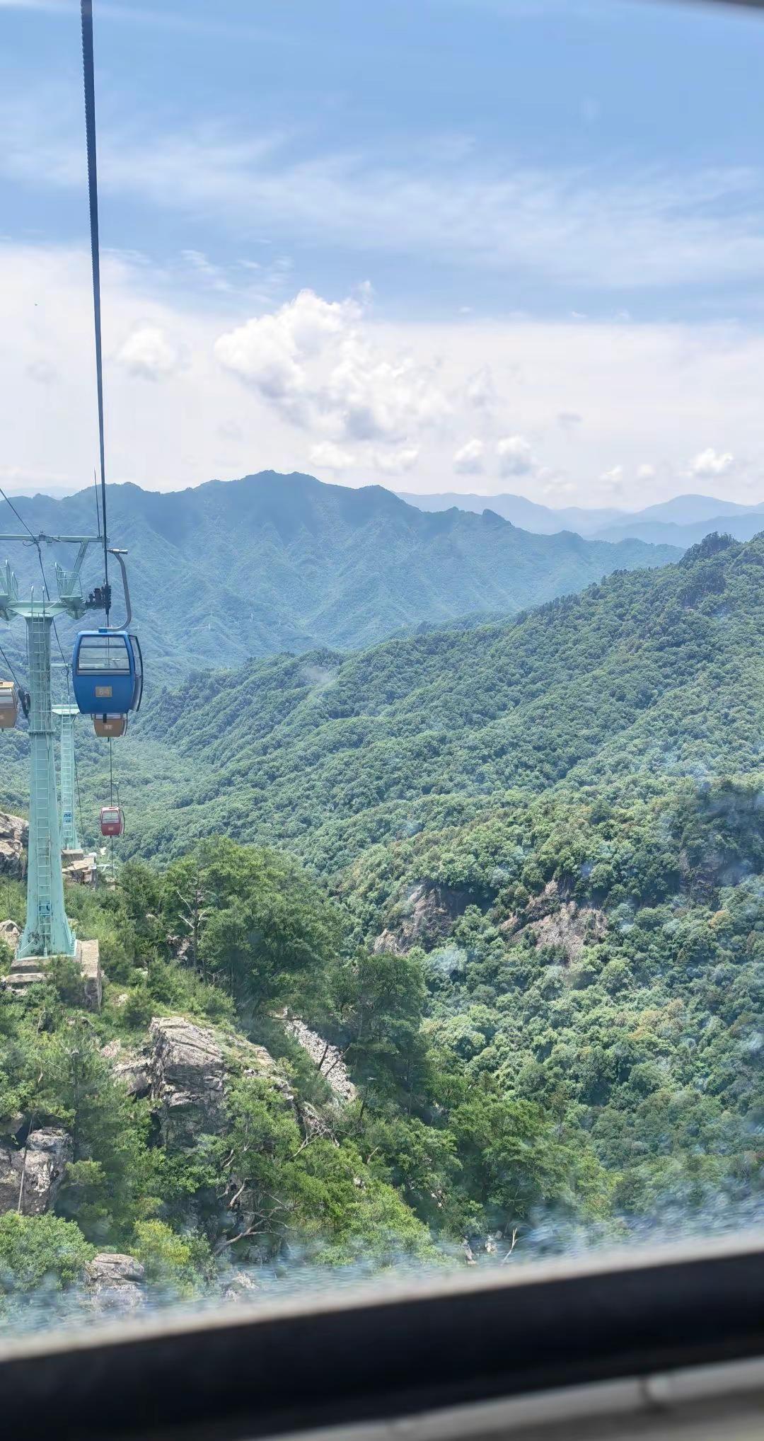 缆车缓缓上升，眼前的风景如画卷般展开。青山绿水间，仿佛置身于仙境。远处的山峦层叠