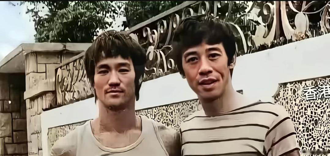 两位男士在墙边合影，背景有中文，这应该是70年代的一张合影。有认识右边这位的吗？