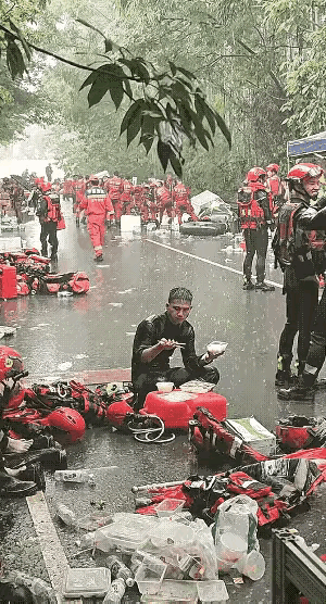 这一幕，看得我鼻子直发酸！广西贵港，消防战士在救援间隙坐在地上吃饭，一阵暴雨突然