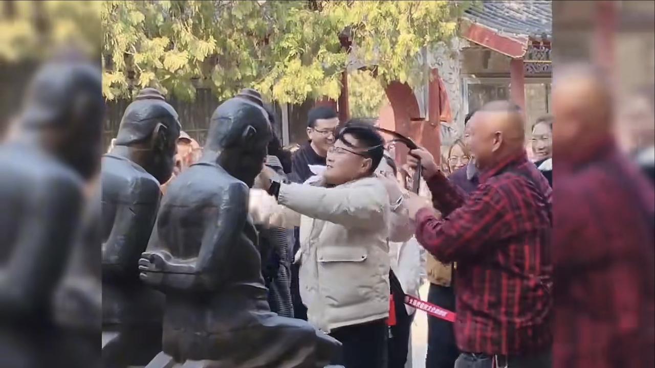 很解压！但也别用力过猛。两名男子在某景区用皮带对着岳飞目前跪着的5个石像宣泄内心