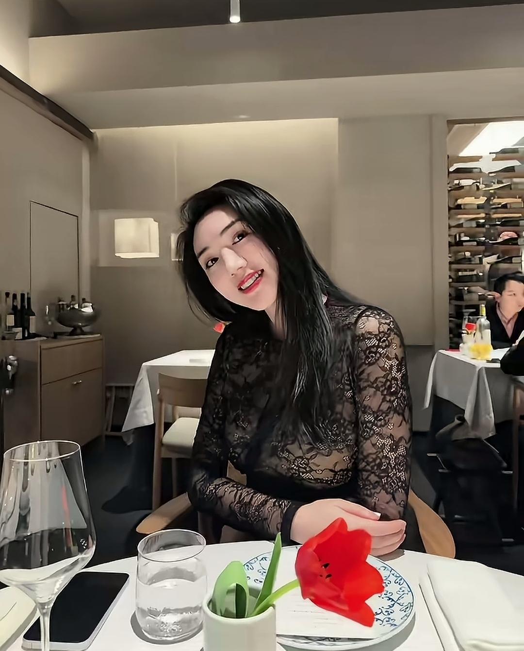女孩在餐厅微笑自拍，背景有其他客人。