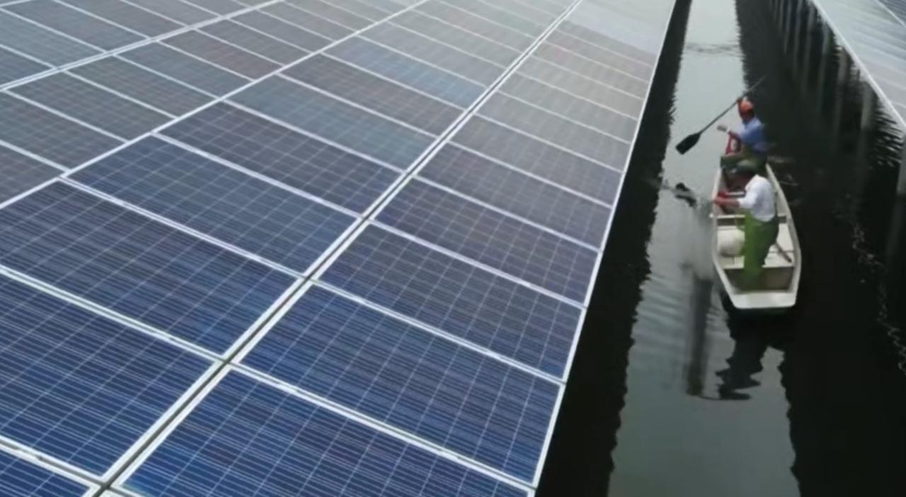 在碧波之上与青山之间，蓝色的光伏板如巨大的能量矩阵铺陈开来。工作人员划着小船穿梭