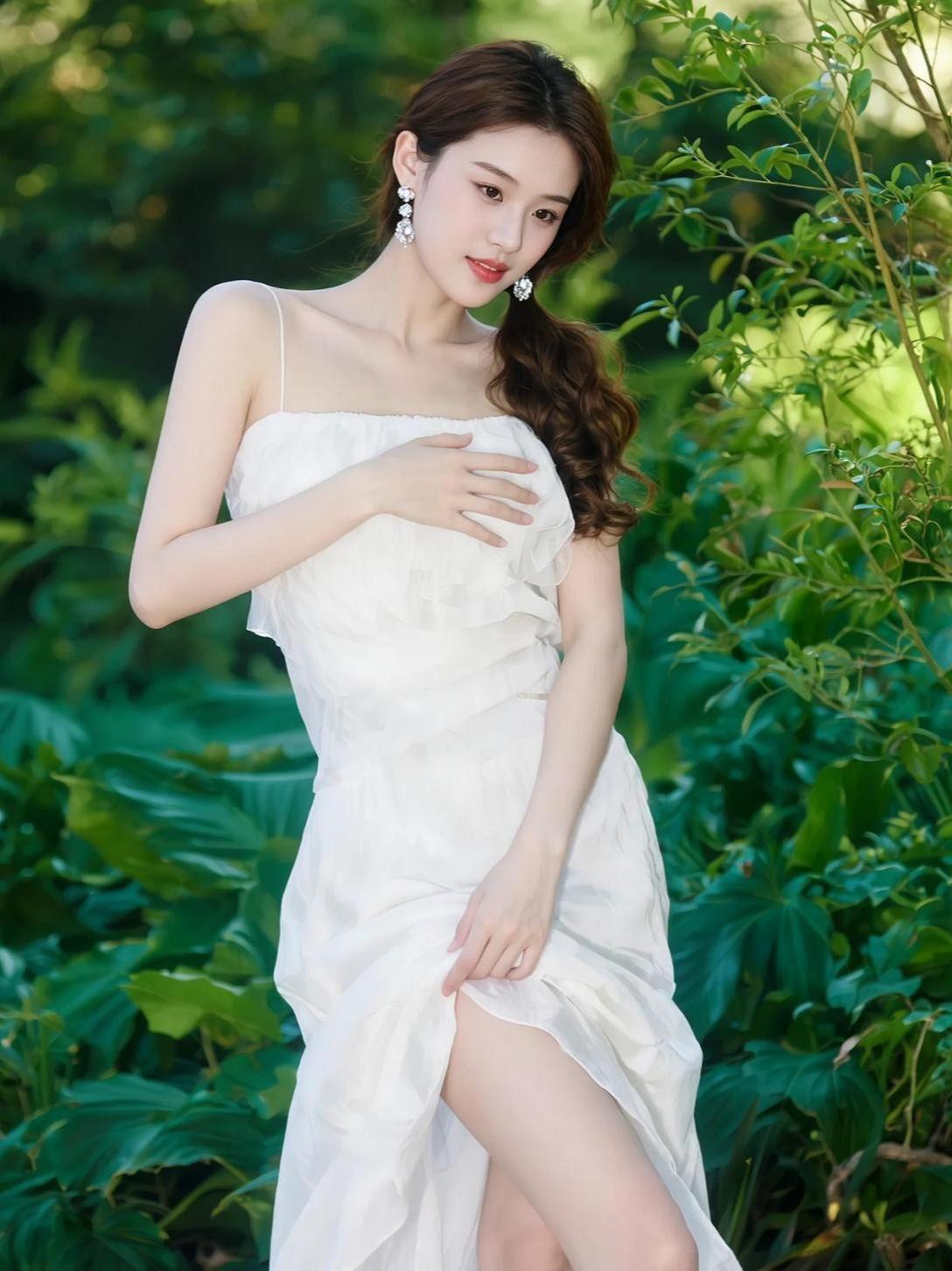 绿意漫过肩头，白裙轻扬如风中的诗行。她站在自然的呼吸里，像一帧被时光定格的画。阳