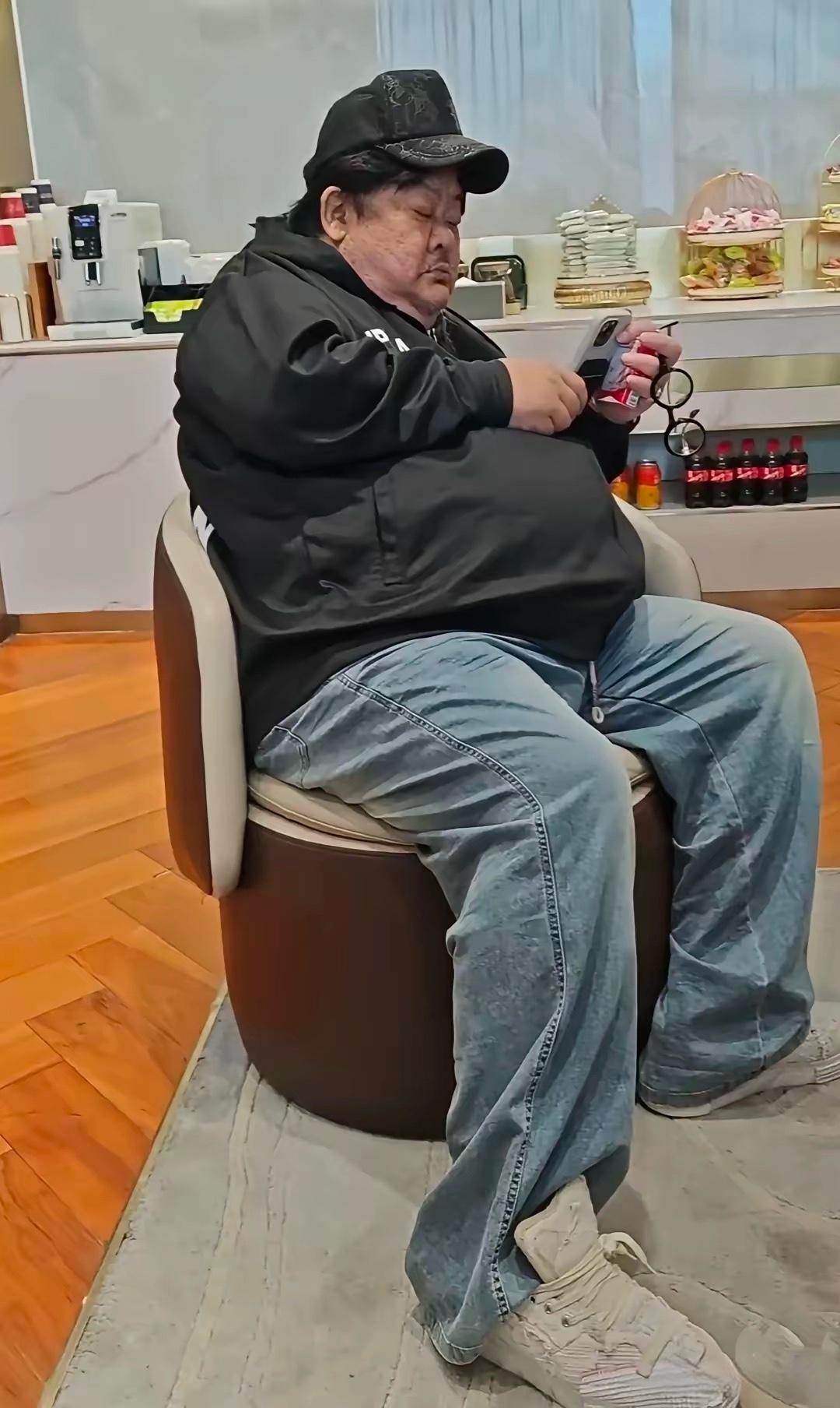 香港演员林雪近照，他戴着棒球帽，身穿休闲服，坐在那里看手机的画面。

林雪在香港