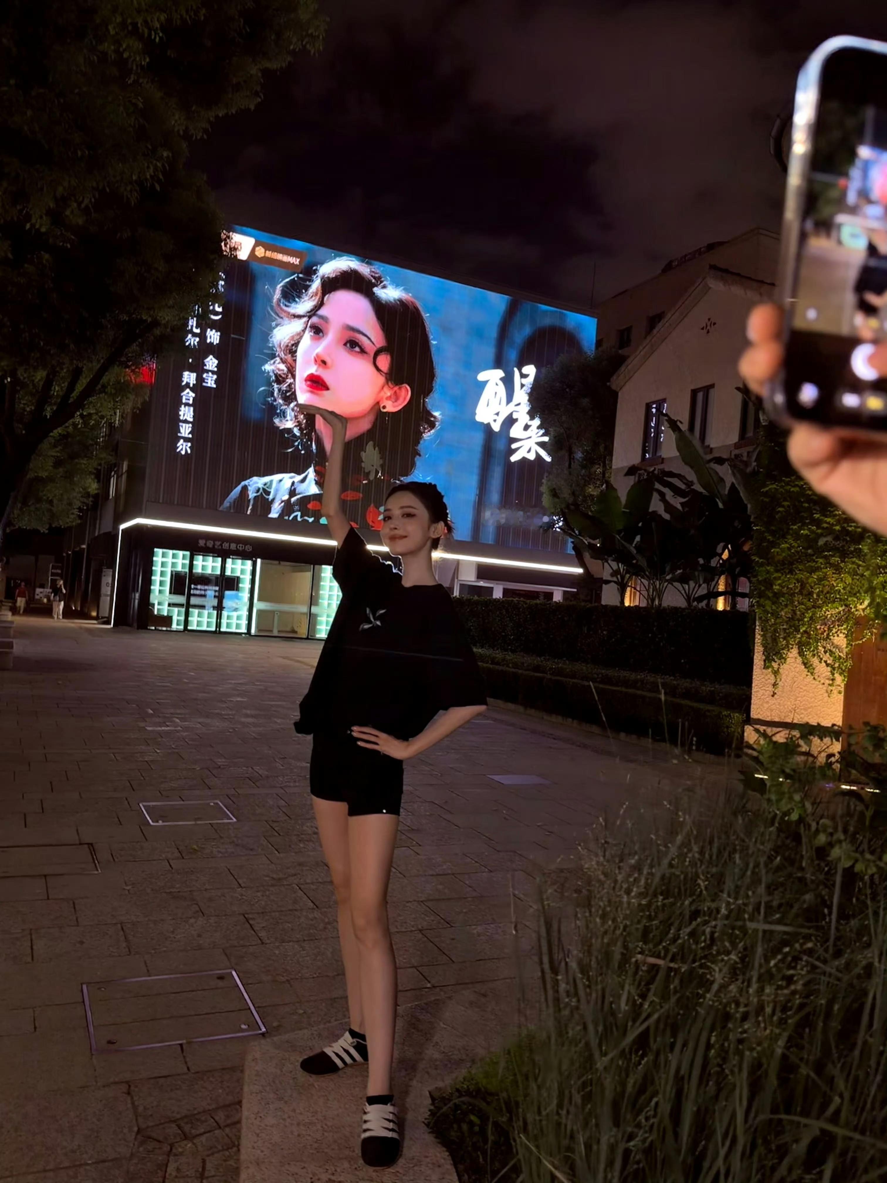 娜扎线下打卡自己角色大屏。荧幕之上是角色金宝，站在灯火之下的本人，颜值更加抓人，