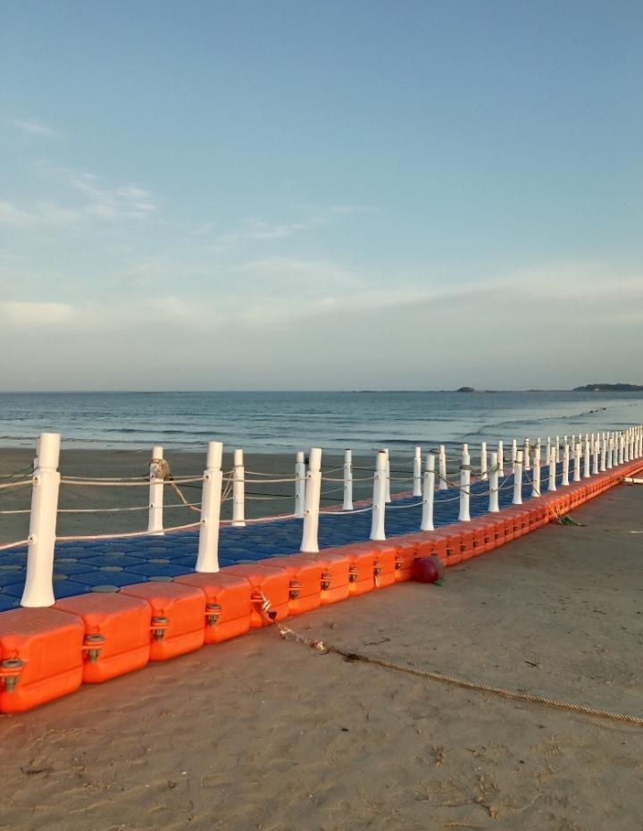 上周加班熬了整宿，特意抽傍晚跑来这片海边。看着这条橙蓝浮桥一直延伸到海面，吹着海