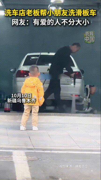 “太暖心了！”，男孩骑着自己的滑板车在路边玩，经过一家洗车店，看到老板在洗车，原