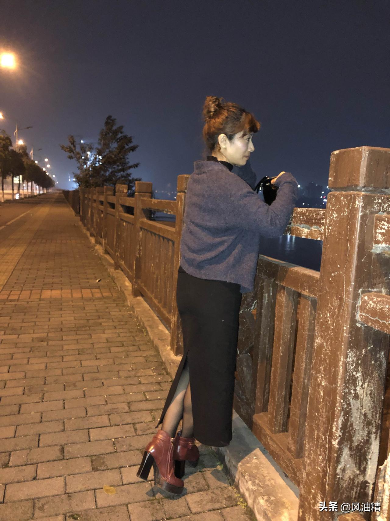 夜色温柔，江风轻拂。她倚着斑驳木栏，丸子头蓬松慵懒，灰调针织衫衬得身姿温婉，开叉