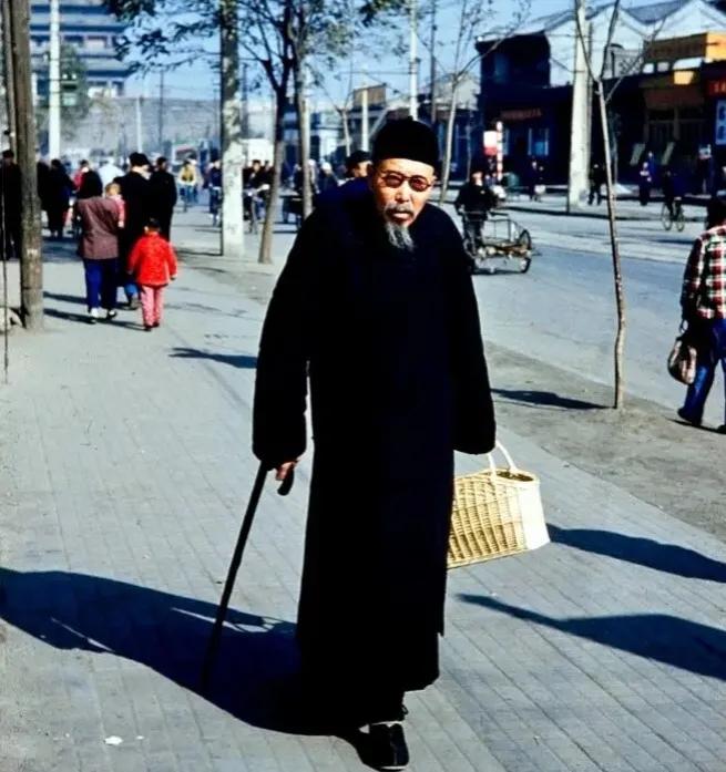 1959年，北京街头，一位散步的老人，他的打扮非常独特，头戴一顶厚重的棉帽，身穿