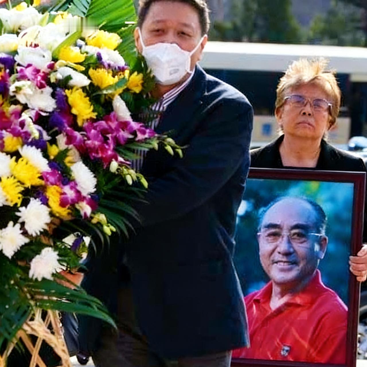 2013年，乒乓球运动员庄则栋出殡仪式上，妻子佐佐木墩子抱着丈夫的遗像，她神情肃