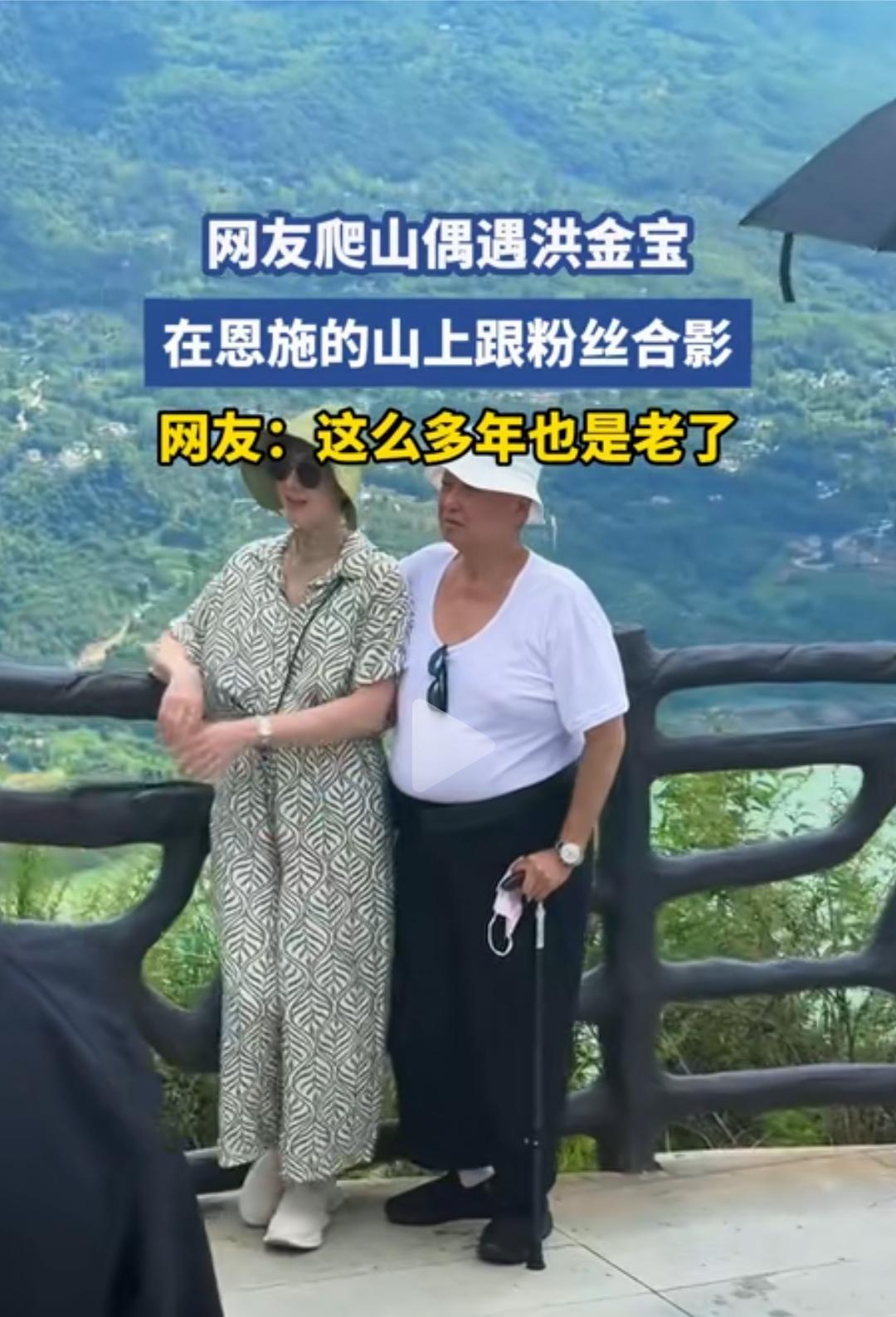 洪金宝在恩施的山上被网友偶遇，他戴着遮阳帽，白色短袖，挺着大肚腩，拄着拐杖，虽然