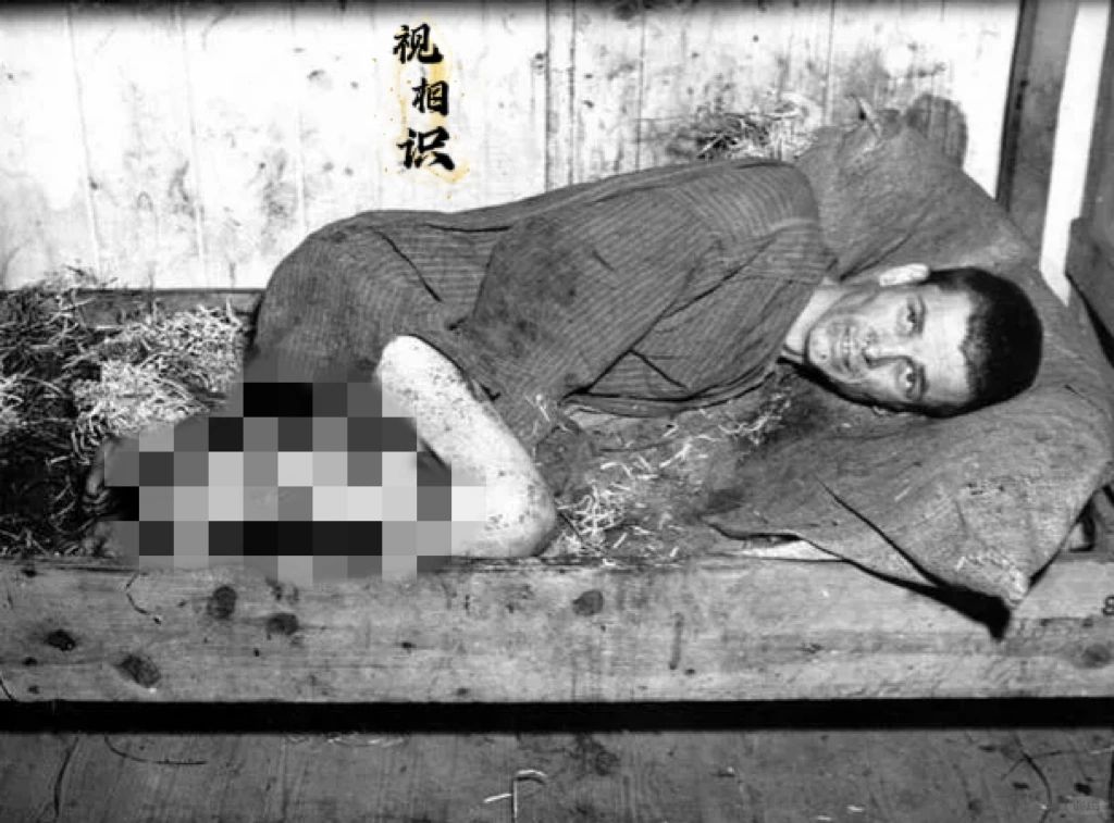 1945年，盟军解放纳粹集中营时，其中一处场景，画面中一名囚犯蜷缩在肮脏不堪的床...