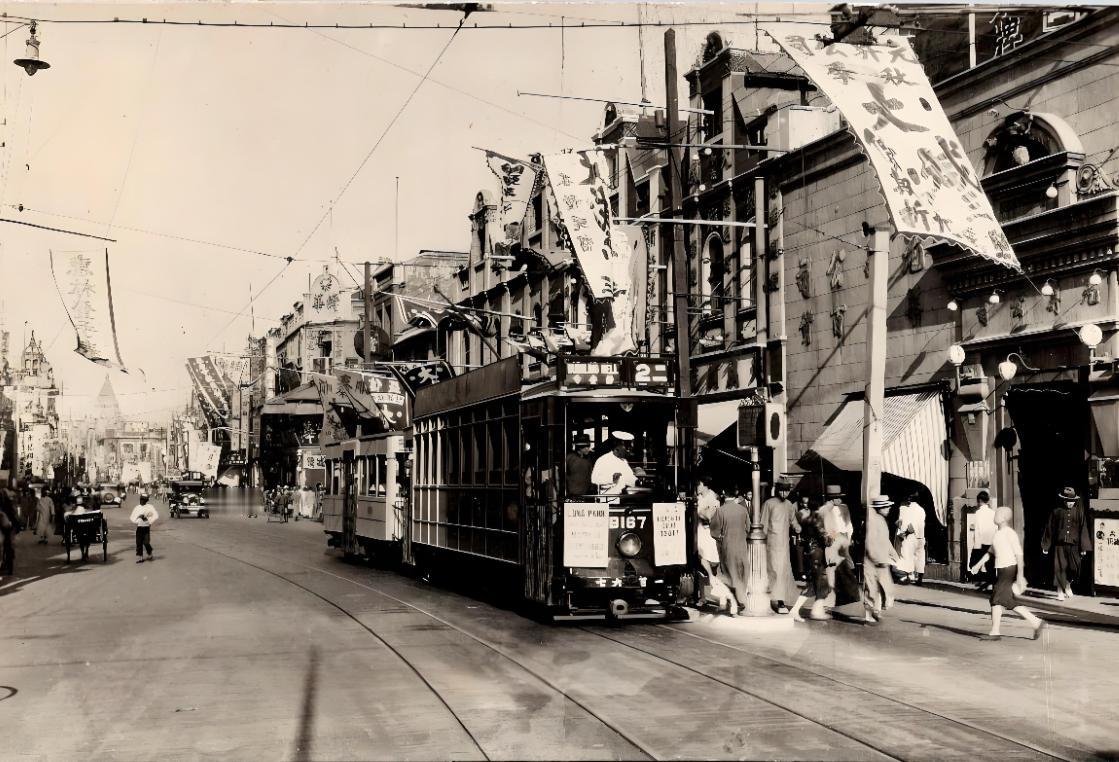 淞沪会战之前的上海街头。
一辆电车徐徐驶来，
街道上的招牌随处可见，
人们戴着帽