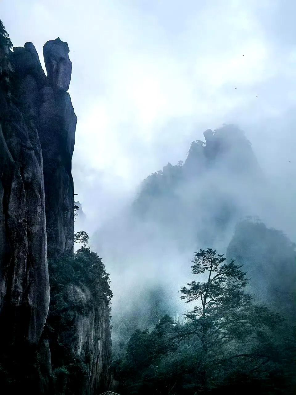 三清山的雨雾就像天然的幕布，将孤清与浩荡的气质完美融合。那云纱漫卷之处，仿佛藏着