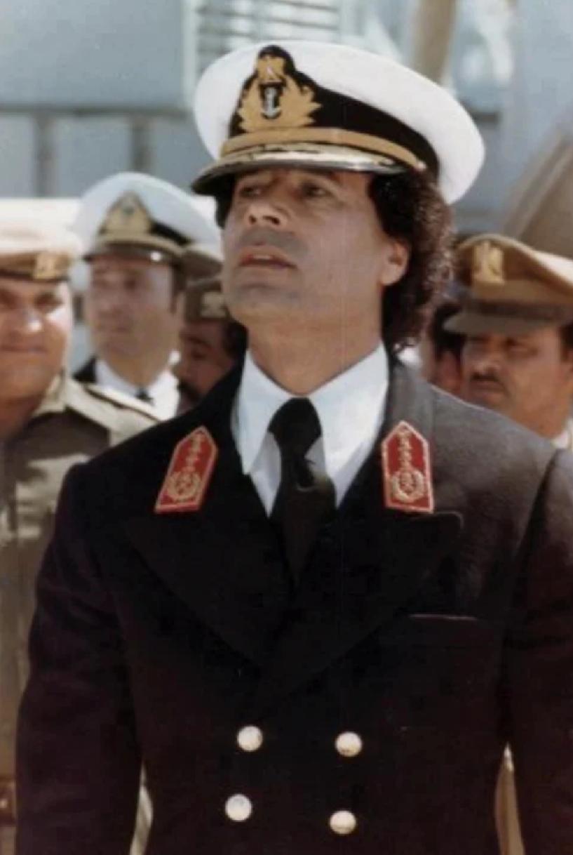 卡扎菲戎装在身，昂首挺胸，意气风发，是个美男子。
卡扎菲坐在众多美女中间，穿着休