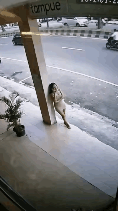 国外一名女子靠着柱子打电话，一条流浪狗突然冲过来对着她不停狂吠。女子误以为狗狗要
