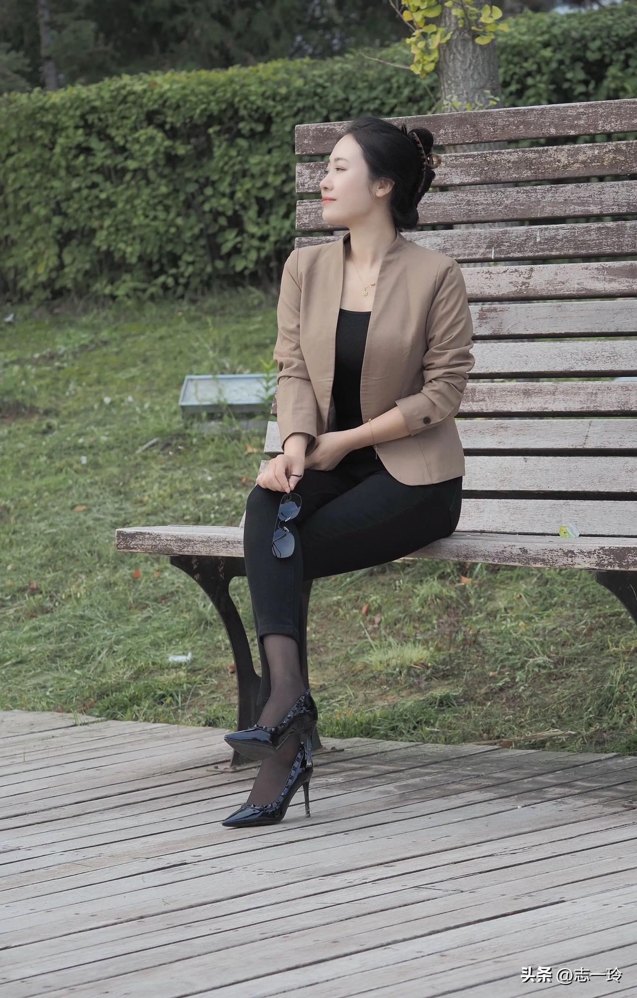 一个穿得漂亮的女人坐在公园长椅上。