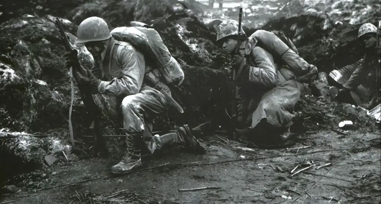 照片拍摄于1945年2-3月的硫磺岛战役期间。画面中的美军陆战队员正蜷缩在泥泞的
