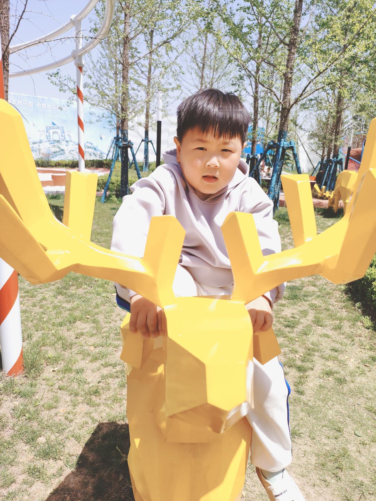 看着这张照片，真的能感受到孩子简单又纯粹的快乐！小家伙坐在亮黄色的小鹿雕塑上，背