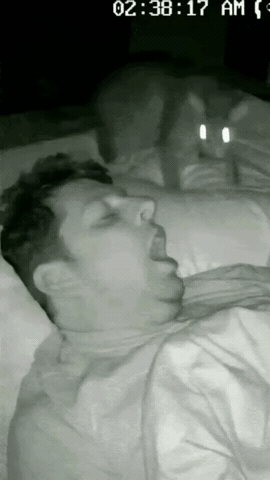 男子正躺在床上呼呼大睡，还张开嘴巴呼吸，家里养的狸花猫看到了，还以为男子是饿了，